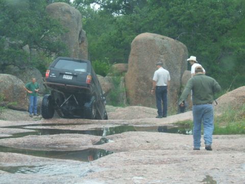 1995 Ford Bronco - A black Toyota 4Runner navigates a rocky terrain with several onlookers present.