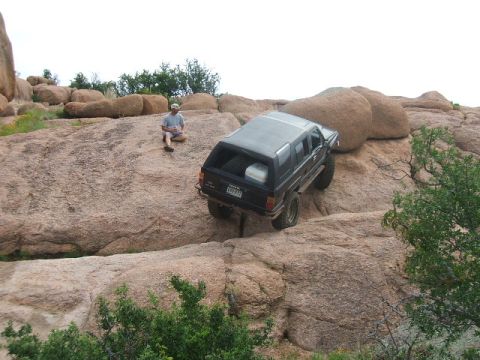 1995 Ford Bronco - A man sits on a rock while a black SUV navigates a rocky terrain.