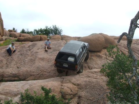 1995 Ford Bronco - SUV navigating a challenging rocky terrain with spectators observing the climb.