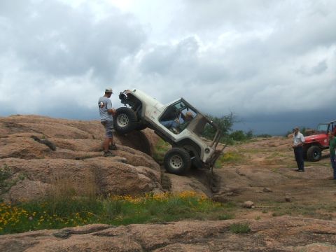 1995 Ford Bronco - Two Jeeps off-roading on a rocky terrain under a cloudy sky.