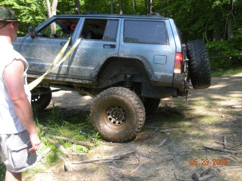 1998 Chevrolet Blazer - A blue SUV with off-road modifications is seen on a dirt trail, with a person standing nearby.