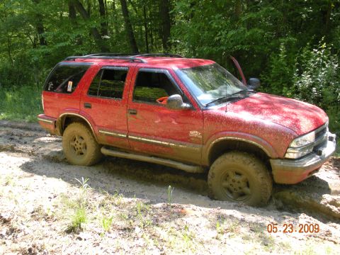 1998 Chevrolet Blazer - A red 1998 Chevrolet Blazer is stuck in the mud on a wooded trail.