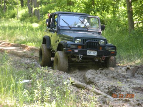1998 Chevrolet Blazer - Jeep Wrangler navigates a muddy path in a forest setting.