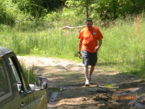 1998 Chevrolet Blazer - A man walks past a green SUV on a muddy path in a wooded area.