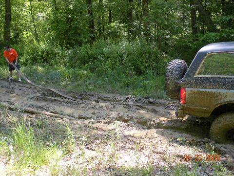 1998 Chevrolet Blazer - A person uses a strap to pull a mud-covered SUV out of a difficult, muddy trail.