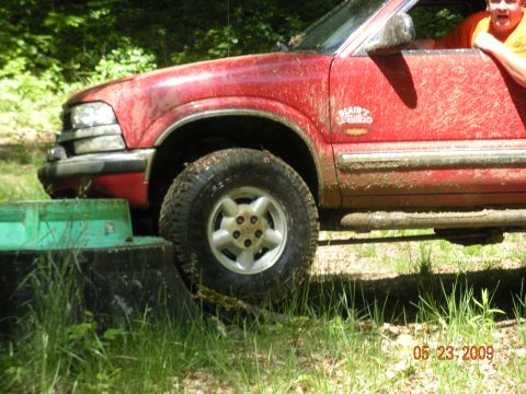 1998 Chevrolet Blazer - A muddy red 1998 Chevrolet Blazer is seen from the side, with a person visible in the driver's seat.