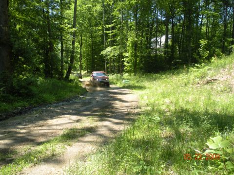1998 Chevrolet Blazer - A red 1998 Chevrolet Blazer navigates a muddy trail surrounded by lush green trees.