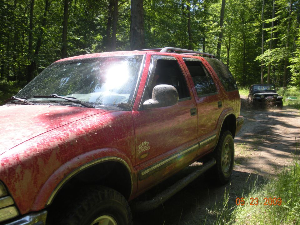 Red 1998 Chevrolet Blazer on a dirt road with another vehicle behind