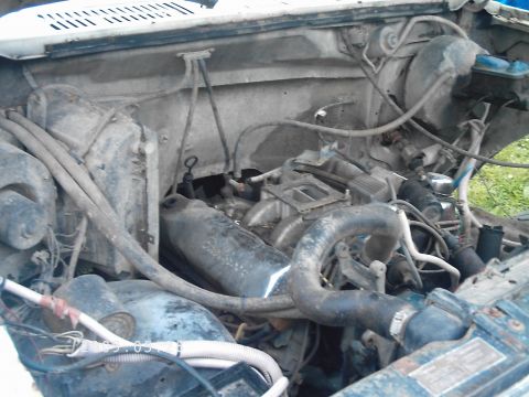 1986 Ford Bronco - The engine bay of a vehicle, showing various hoses, the engine block, and other mechanical parts. A watermark indicates the source as SUPER…