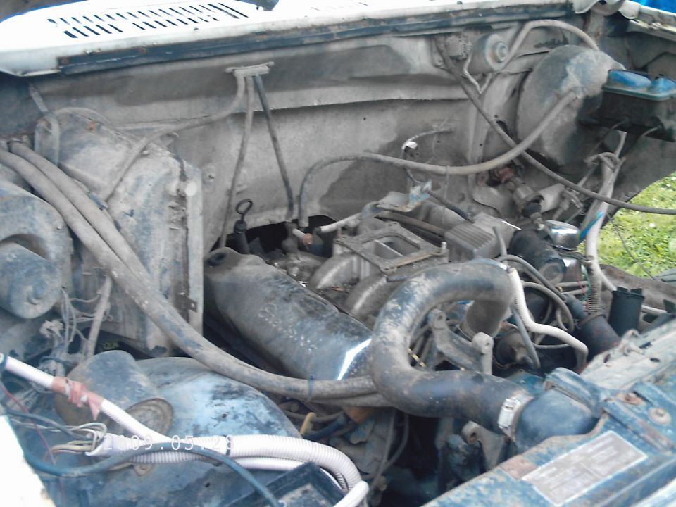 Engine bay with visible hoses and engine components. Watermark reads SUPERMOTORS