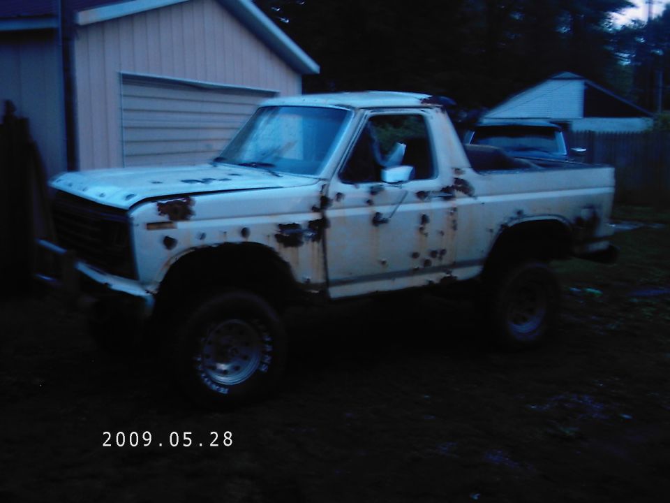White SUV with significant rust damage parked in front of a garage. Date stamp reads 2009.05.28