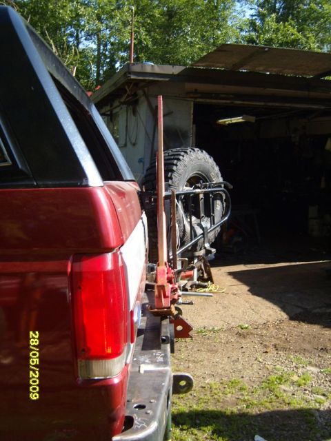 1989 Ford Bronco - The rear of a red SUV is shown, a spare tire and a jack mounted on the bumper assembly.
