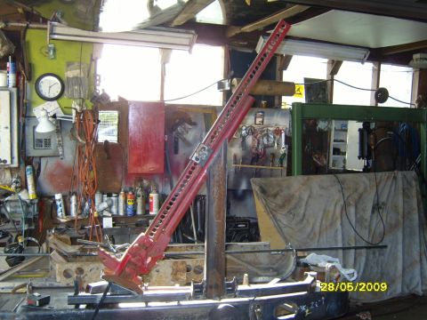 1989 Ford Bronco - A red hi-lift jack is positioned in a workshop setting, with various tools and equipment in the background.