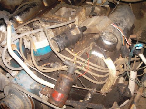1986 Ford Bronco - A close-up view of a cluttered engine bay with various wires and engine parts.