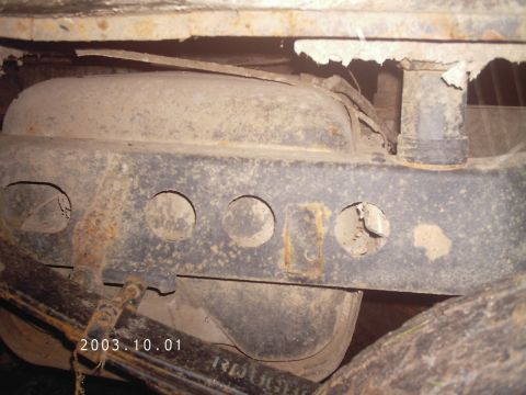 1986 Ford Bronco - Close-up of a vehicle's rusty undercarriage components, including the frame and fuel tank.