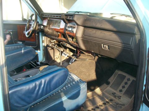 1982 Ford Bronco - The interior of the truck features blue vinyl seats, a wood-grained dashboard, and a radio.
