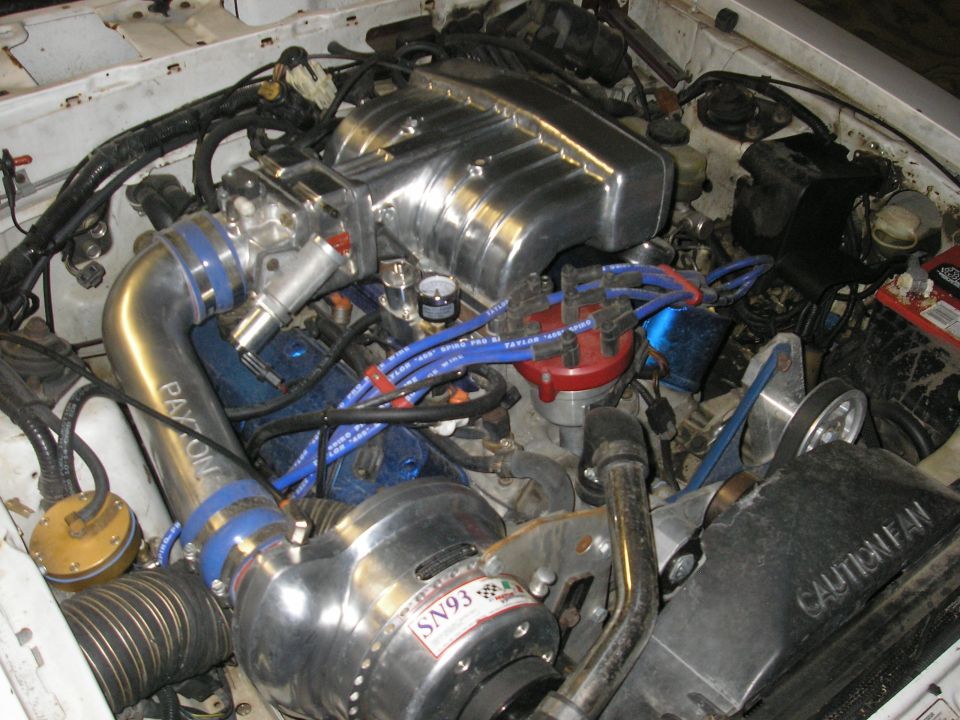 V8 engine bay with polished centrifugal supercharger and blue spark plug wires