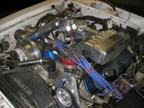 1979 Ford Bronco - Close-up of a modified engine bay a supercharger and prominent blue spark plug wires.