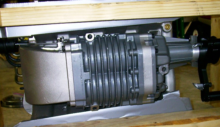 Roots-style supercharger unit resting on wood blocks on a workbench