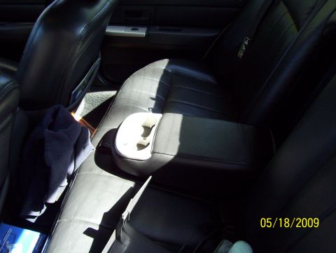 2003 Ford Crown Victoria - Interior view of a vehicle's rear seats, a center console with a cup holder and a folded blue cloth on the seat.