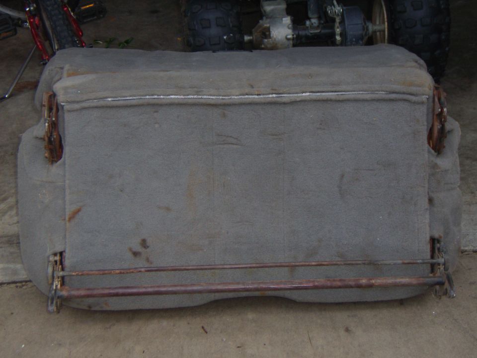 Gray fabric car seat with exposed metal frame and rust