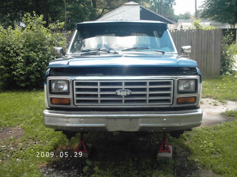Blue SUV front end on jack stands, chrome grille, square headlights