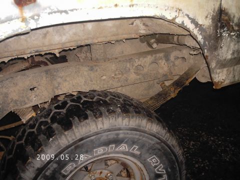 1986 Ford Bronco - The undercarriage of a vehicle shows significant rust and wear on the frame and suspension components.
