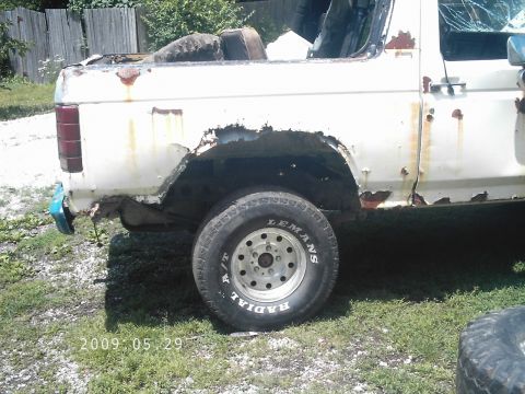 1986 Ford Bronco - Heavily rusted white SUV, likely a Ford Bronco from the 1980s, seen from the side.
