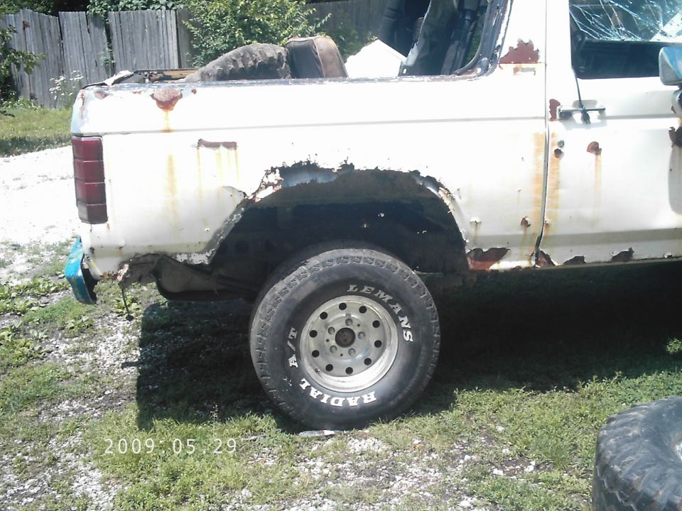 White SUV rear side, heavily rusted. Tire visible. Date stamp 2009 05 29
