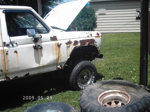 1986 Ford Bronco - This heavily rusted pickup truck has a broken windshield and its hood is propped open.