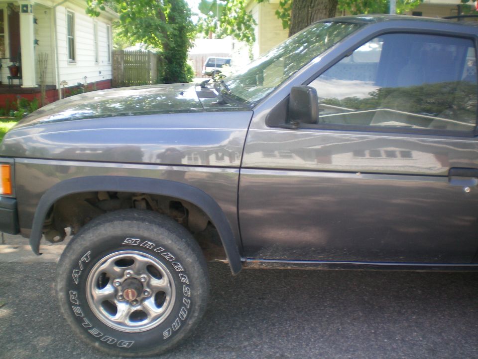 Side view of a gray 1993 Nissan Pathfinder SUV parked outside a house