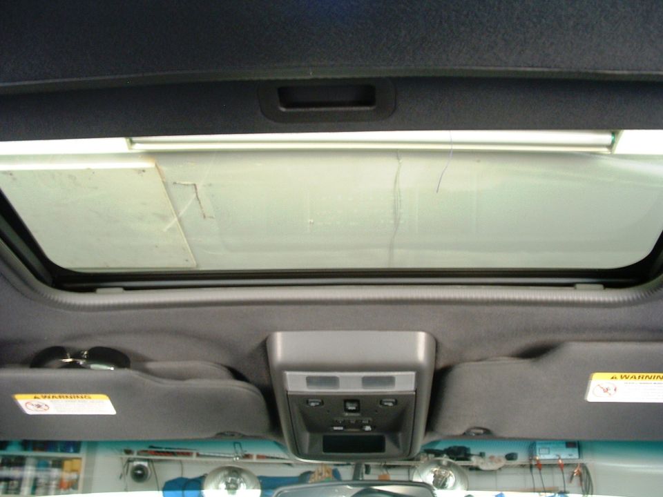 Open vehicle sunroof viewed from inside showing headliner and overhead console