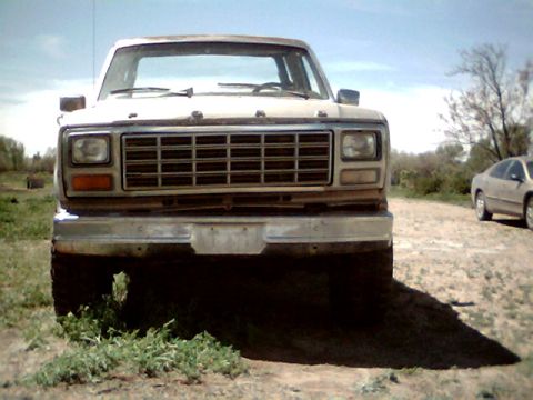 1981 Ford Bronco - Frontal view of an older model Ford pickup truck parked outdoors. A second vehicle is visible in the distance.