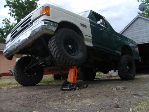 1989 Ford Bronco - This lifted pickup truck, likely from the late 1980s, is elevated on jack stands for maintenance.