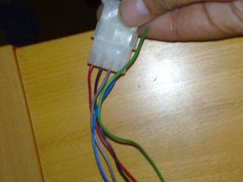 1991 Ford Crown Victoria - A hand holds a white wiring harness connector with several colored wires extending from it.