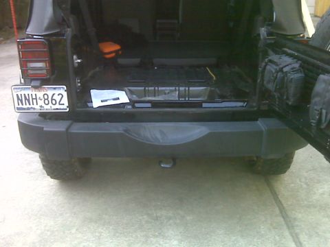 2008 Jeep Wrangler - The rear of a black Jeep Wrangler is shown with its tailgate open, revealing the cargo area and a tow hitch.