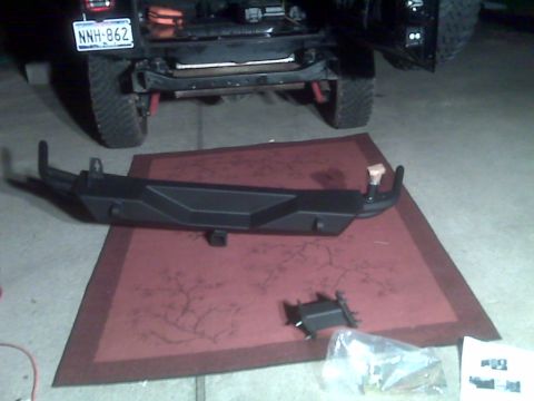 2008 Jeep Wrangler - A Jeep Wrangler is shown with its rear bumper removed, and a new aftermarket bumper is laid out on a mat for installation.