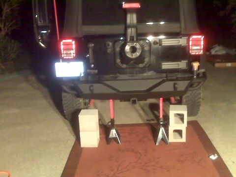 2008 Jeep Wrangler - Night rear view of a Jeep Wrangler with the spare tire removed, showing the bare swing-out tire carrier hub, an aftermarket black steel rea…