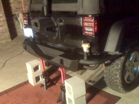 2008 Jeep Wrangler - Installing a new rear bumper on a Jeep Wrangler, supported by jack stands and blocks.