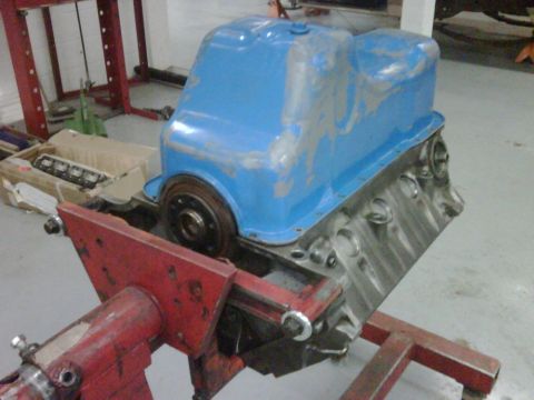 1996 Ford Bronco - Engine block with a blue oil pan mounted on a red engine stand in a workshop.
