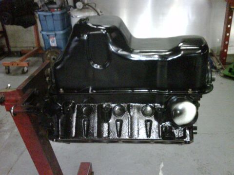 1996 Ford Bronco - A freshly painted engine block and oil pan are mounted on an engine stand in a workshop.
