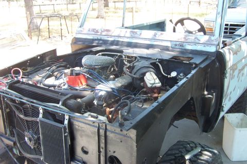1976 Ford Bronco - The engine bay of a 1976 Ford Bronco is shown with the hood removed, revealing the engine and surrounding components.