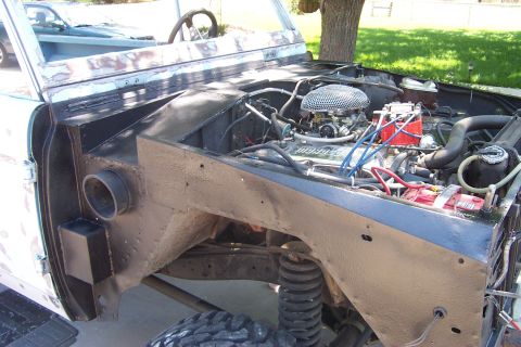 1976 Ford Bronco - The engine bay of a 1976 Ford Bronco shows a V8 engine, likely undergoing restoration or modification.
