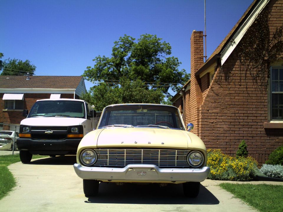 Front of a yellow Ford Falcon Ranchero beside a brick house