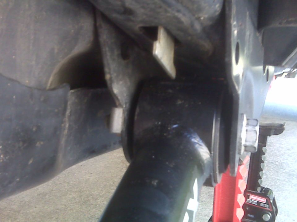 Close-up of black suspension components with silver bolts and red jack stand