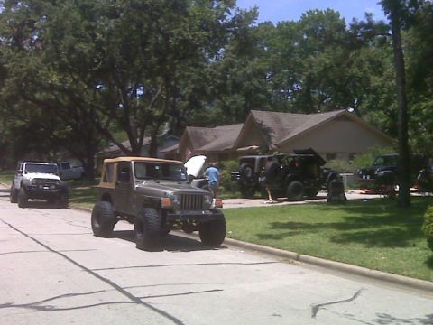 2008 Jeep Wrangler - Multiple Jeep Wranglers are gathered on a residential street and lawn, with one undergoing maintenance.