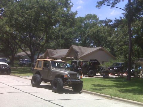2008 Jeep Wrangler - A lifted gray Jeep Wrangler TJ with a tan soft top, rear-mounted spare and oversized mud tires sits at the end of a suburban driveway, seen…