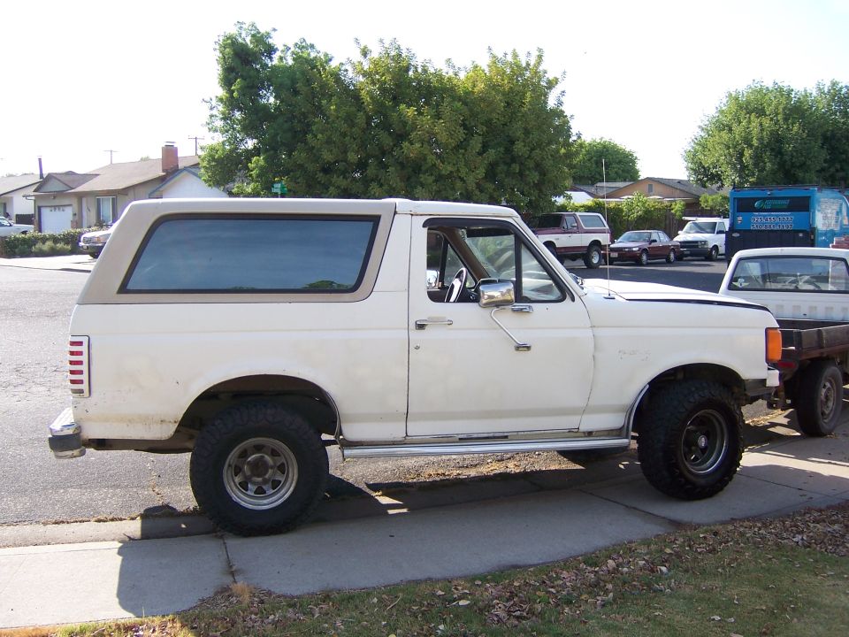 White 1991 Ford Bronco side view with tan top