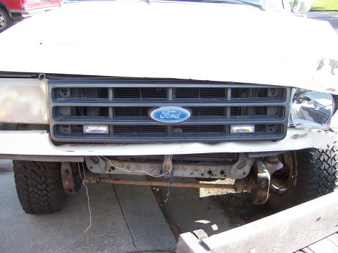 1991 Ford Bronco - Front end damage on a white Ford Bronco, showing the grille and headlights.