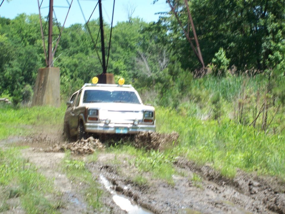 White SUV with yellow lights on roof driving through mud